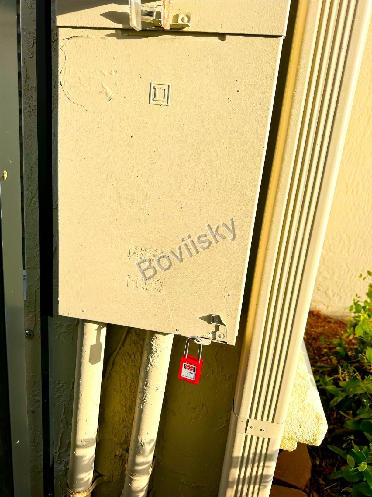 Outdoor electrical disconnect locked out with a red safety padlock