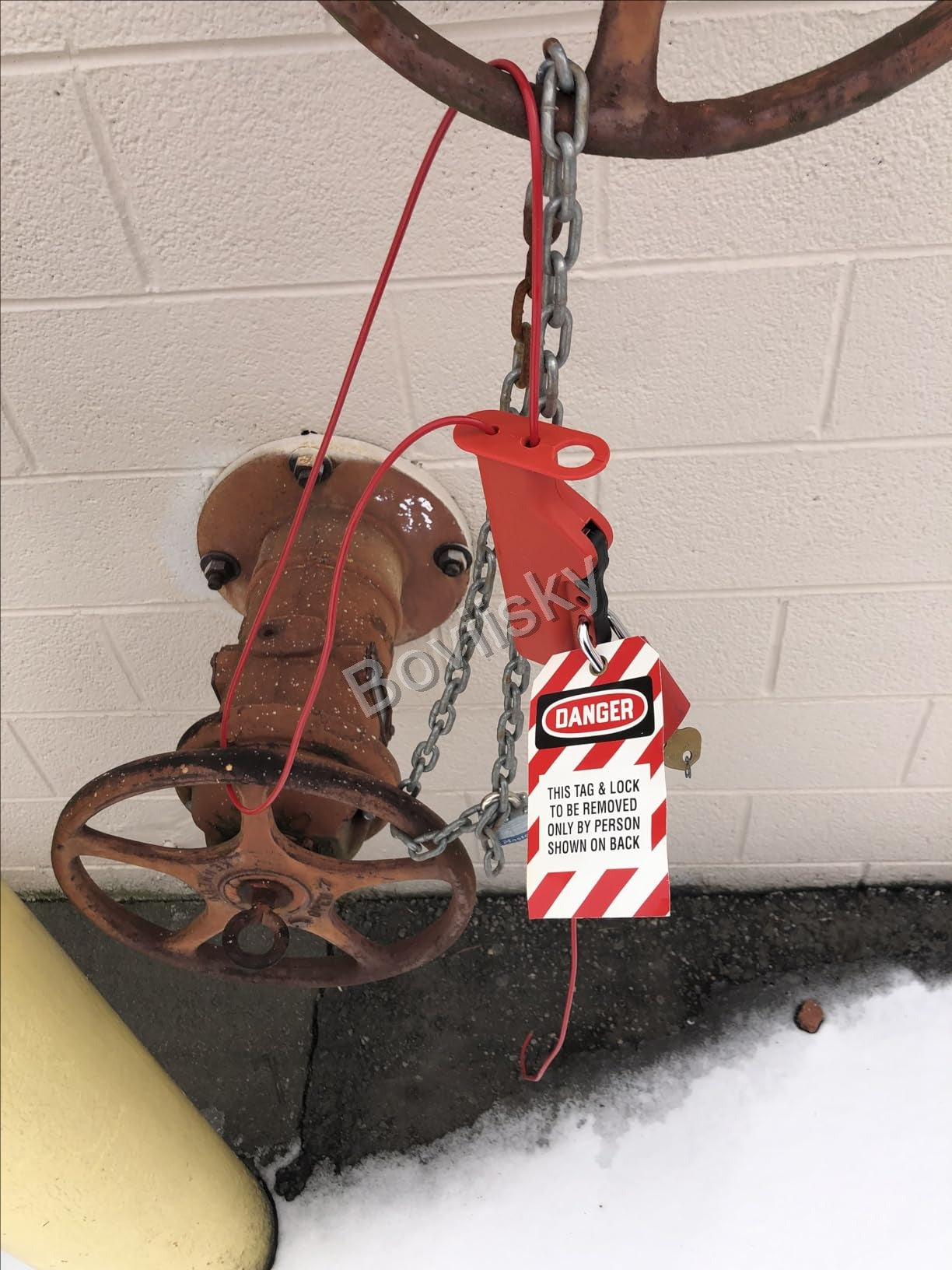 Valve wheel secured with a cable lockout and danger tag